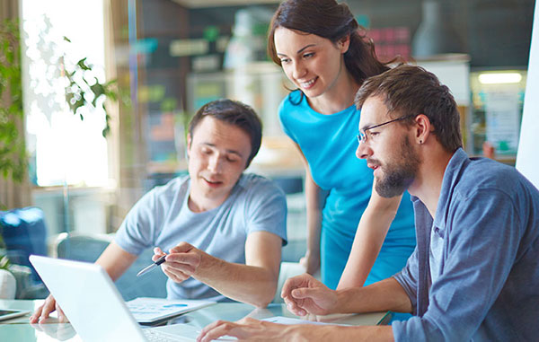 Profesionales colaborando alrededor de un portátil, simbolizando el trabajo en equipo y la compartición de archivos Office en línea.
